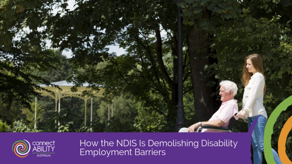 An image of a young woman pushing an elderly man in a wheelchair through a park