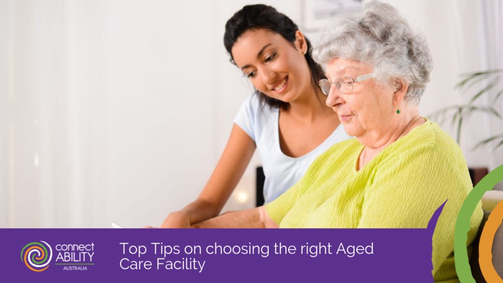 A young woman smiling as she assists an elderly woman with some paperwork