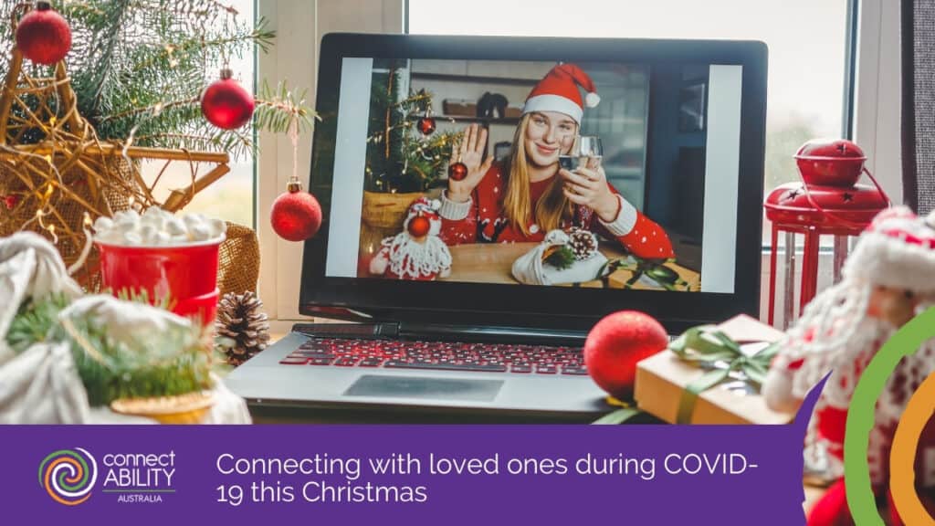 A woman wearing a Santa hat waving on a laptop video call surrounded by Christmas decorations