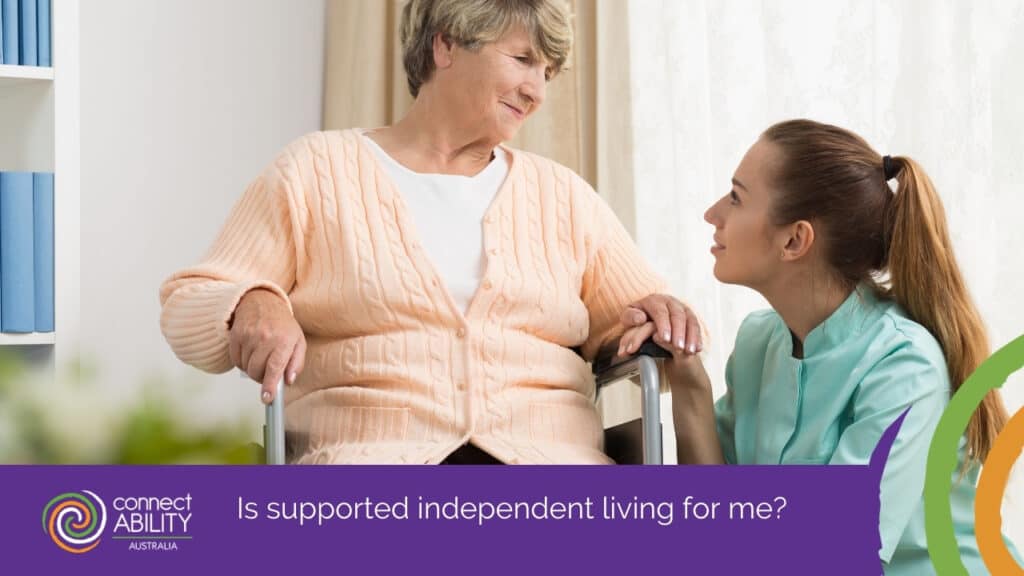 A young female caregiver holding the hand of an older woman in a wheelchair while looking at her with a supportive expression
