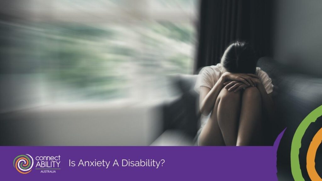 A person sitting on a sofa with their head tucked into their knees in a blurred room