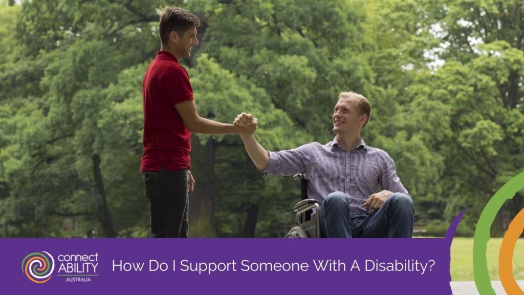 A man in a red shirt shaking hands with a man in a wheelchair in a park setting