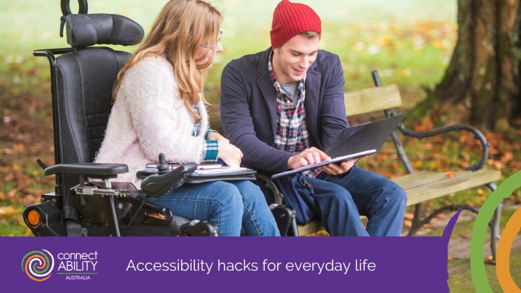 A woman in a motorised wheelchair and a man wearing a red beanie sit together on a park bench