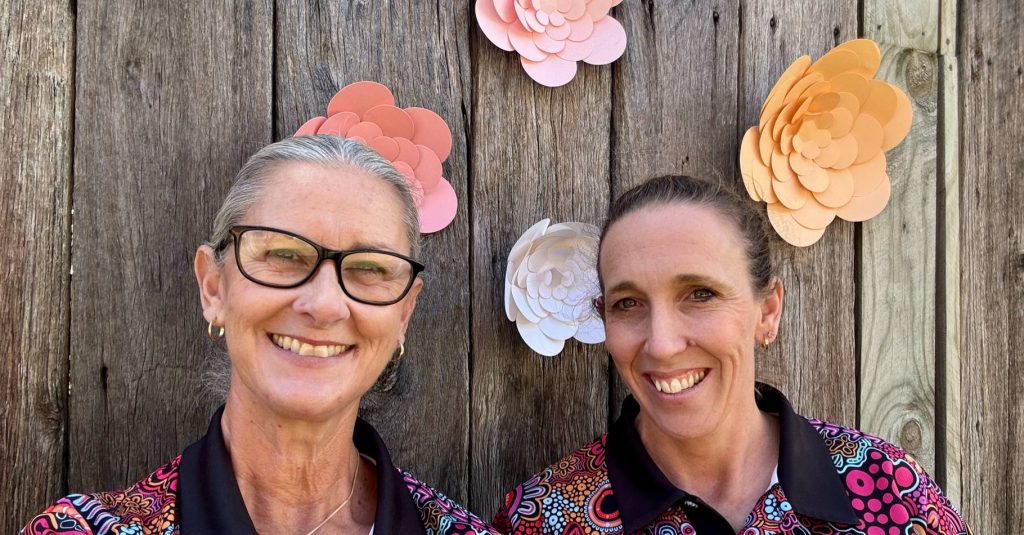 Two smiling women wearing coloorful, Indigenous-style patterned shirts